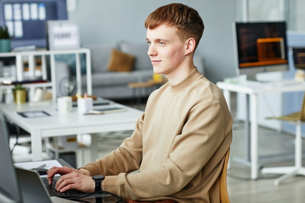 Young man writing programming code on computer